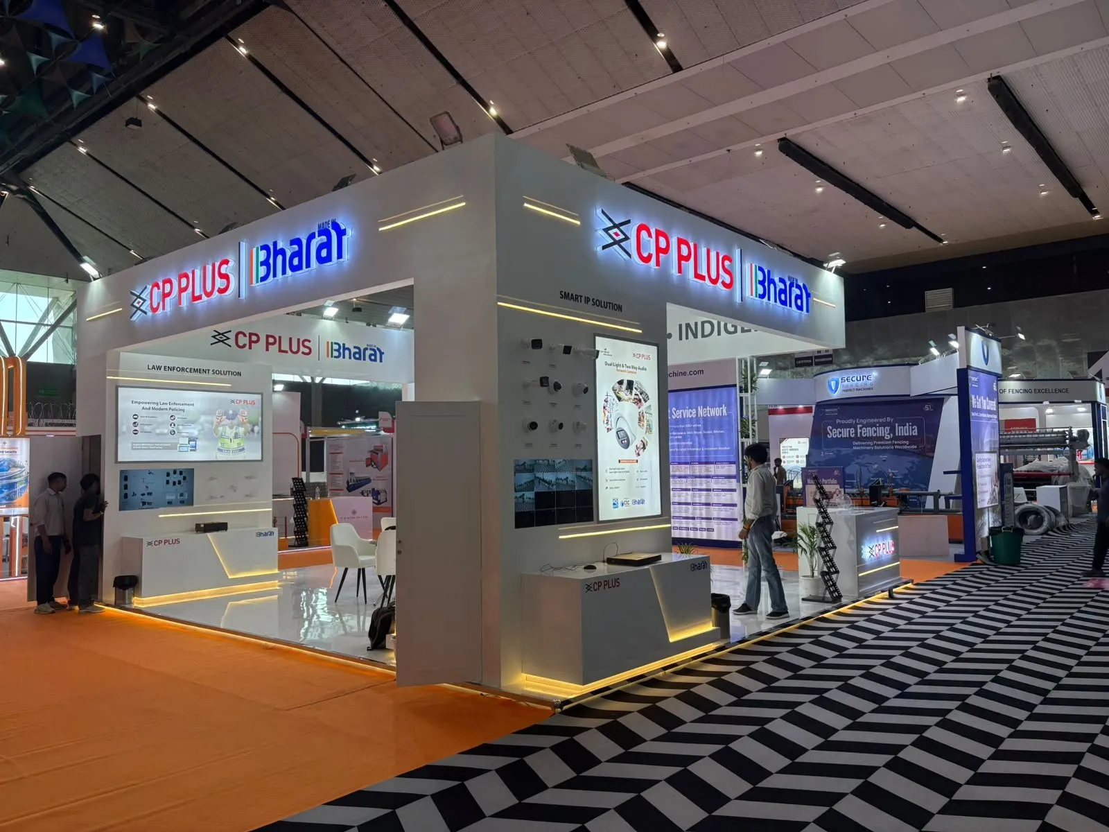 The CP Plus booth from the aisle with the zig-zag carpet and show hall