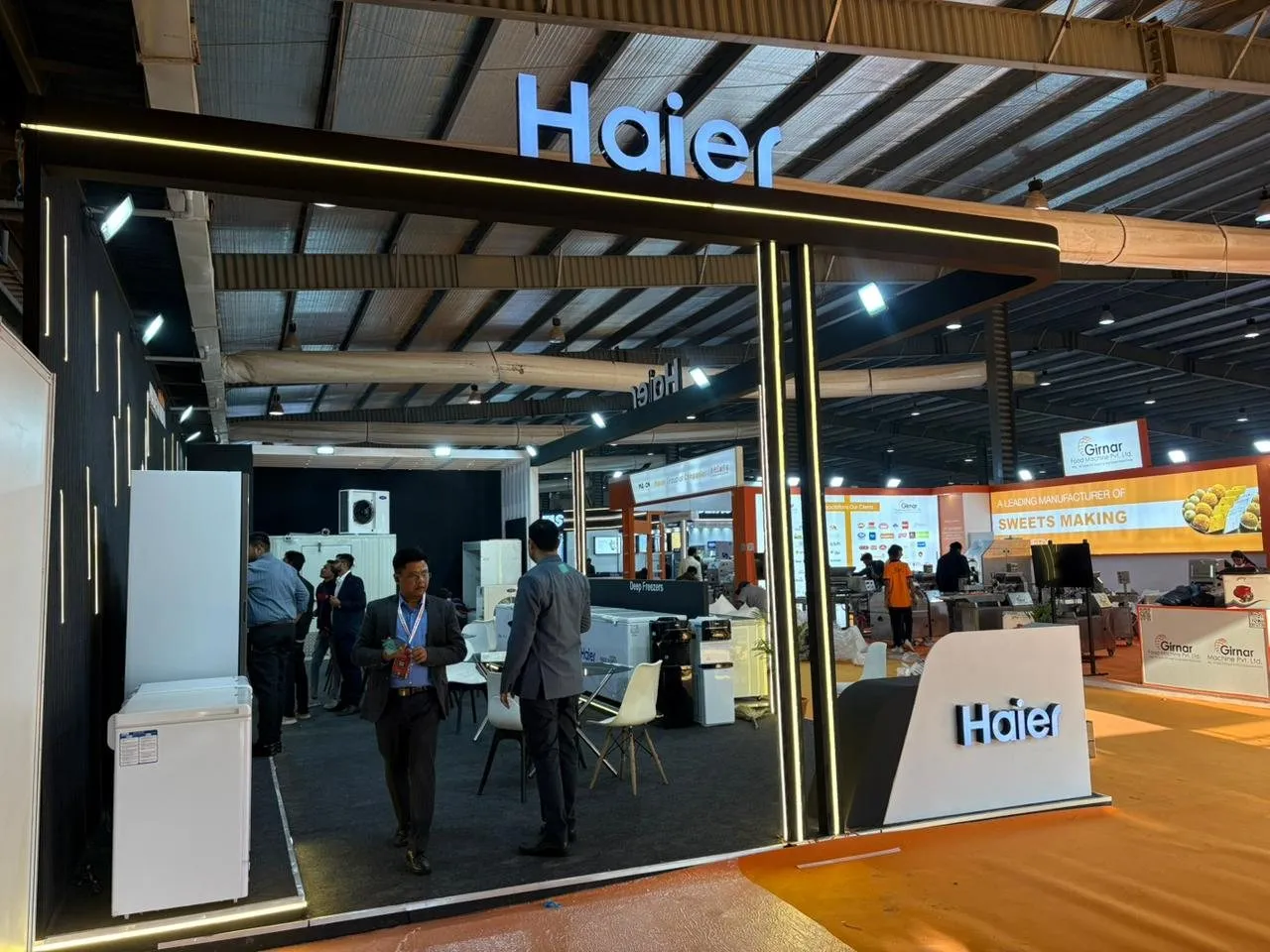 Front of the Haier booth with the lit Haier sign and visitors in the aisle