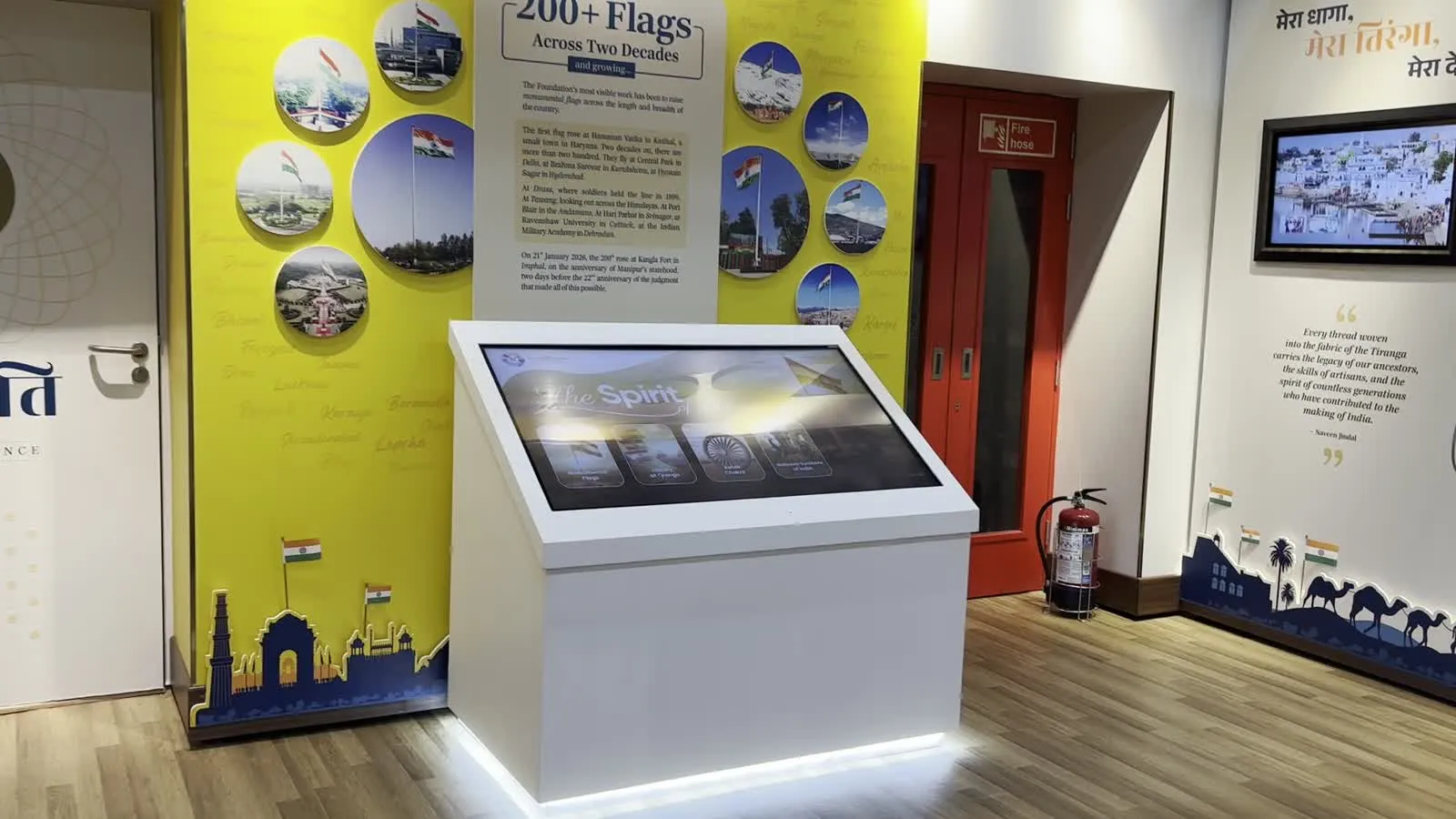 The white kiosk in front of the '200+ Flags Across Two Decades' wall.