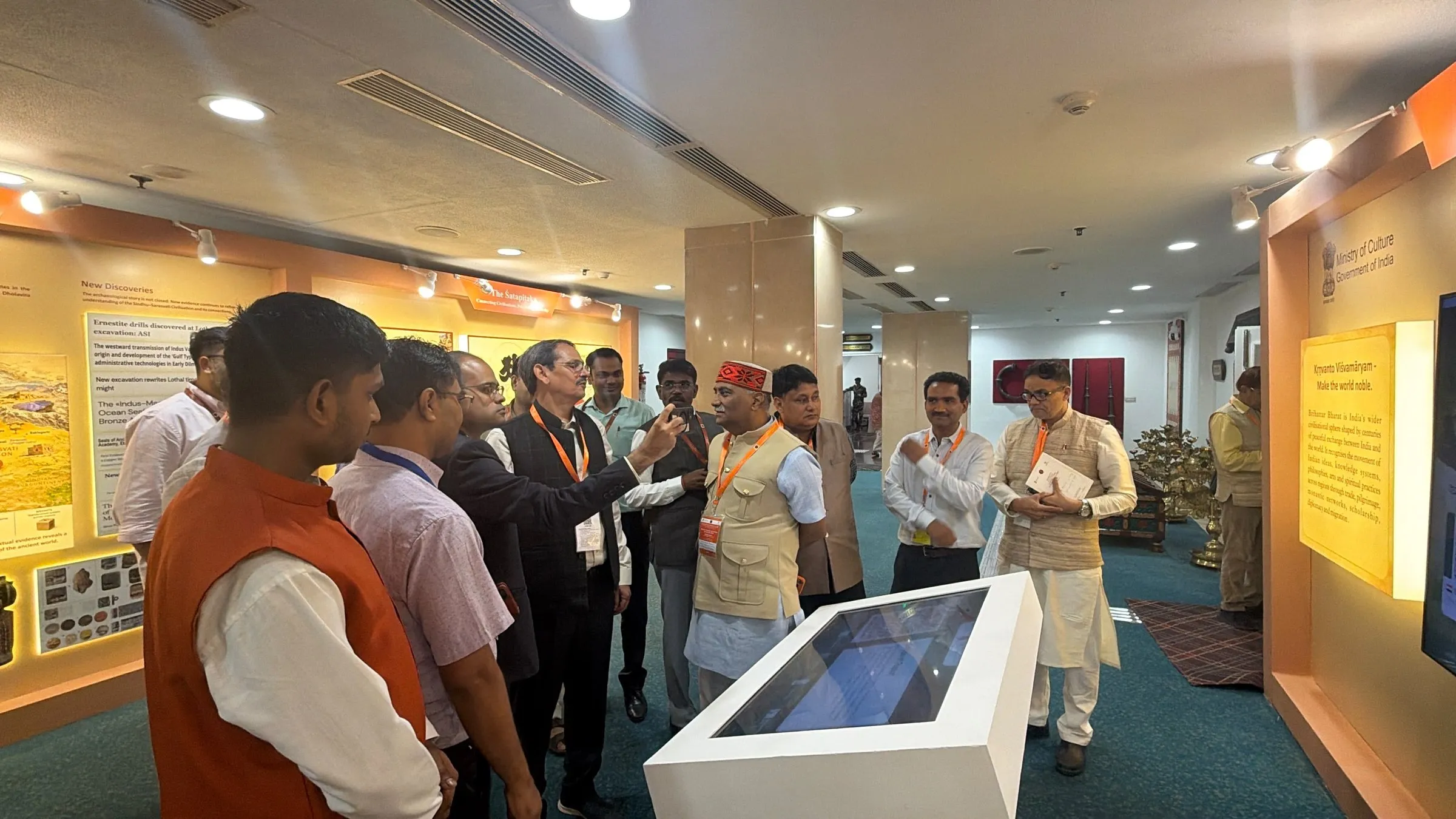 Officials around the white touch table beside the Ministry of Culture wall.
