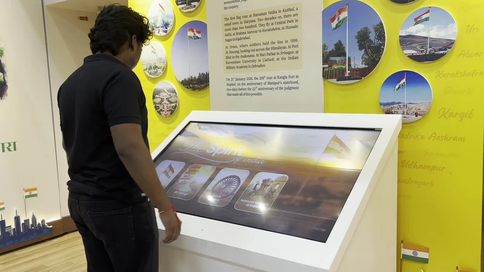 A visitor using the kiosk in front of the yellow flags wall.